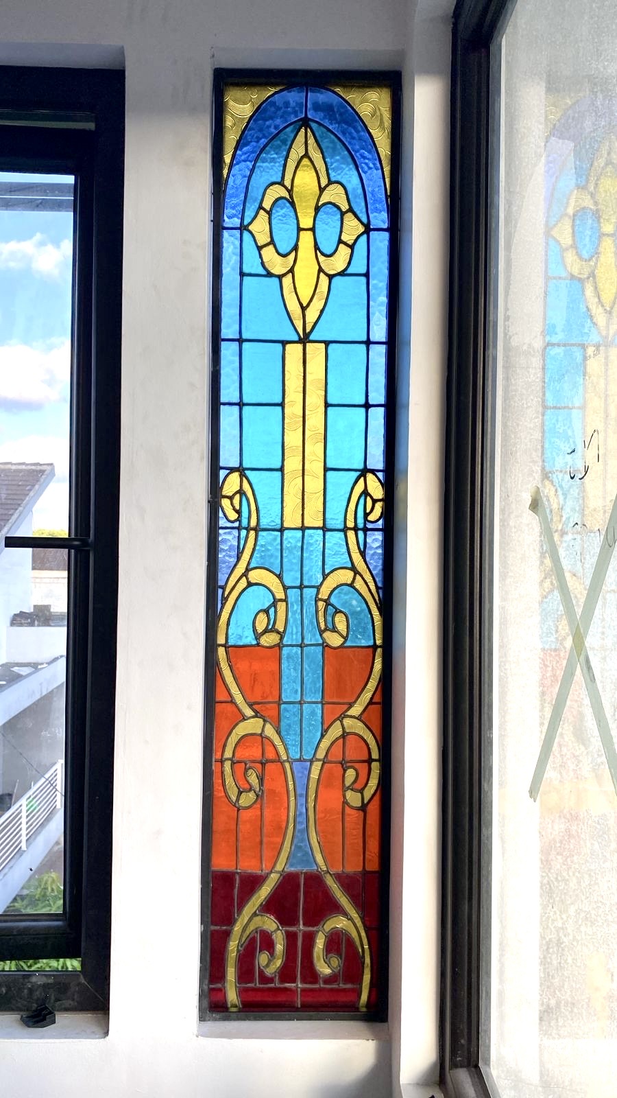 Finished Victorian stained glass panel installed in a Nusa Dua, Bali villa, showing light blue, orange, and red glass.