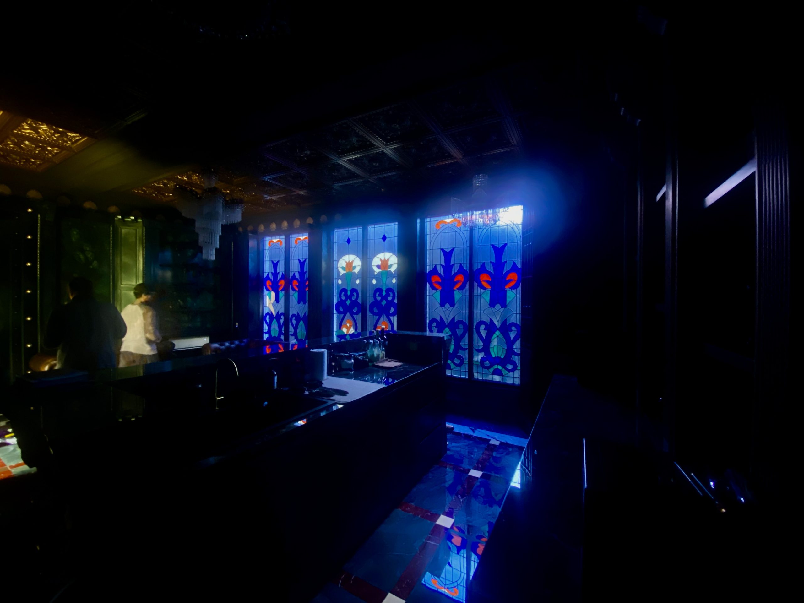 Six blue Art Nouveau stained glass panels behind Chesterfield sofas in a lounge in Kerobokan, Bali